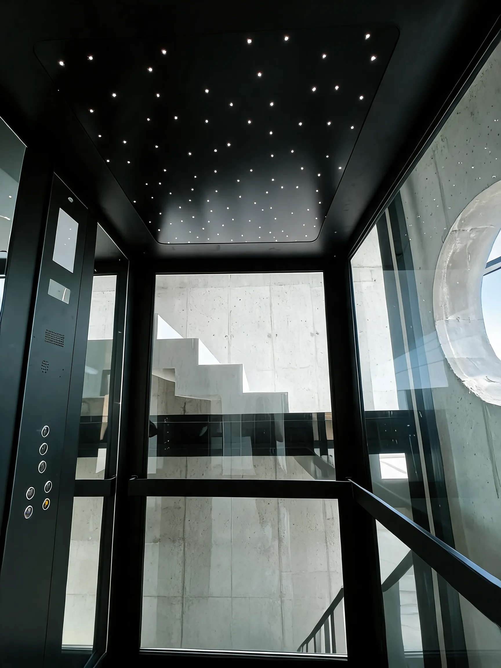 Sufit kabiny z punktami LED i panel dyspozycji, w tle schody z betonu